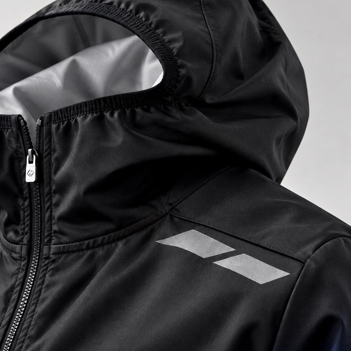 Close-up of a technical jacket hood, zip, shoulder seam and reflective trim